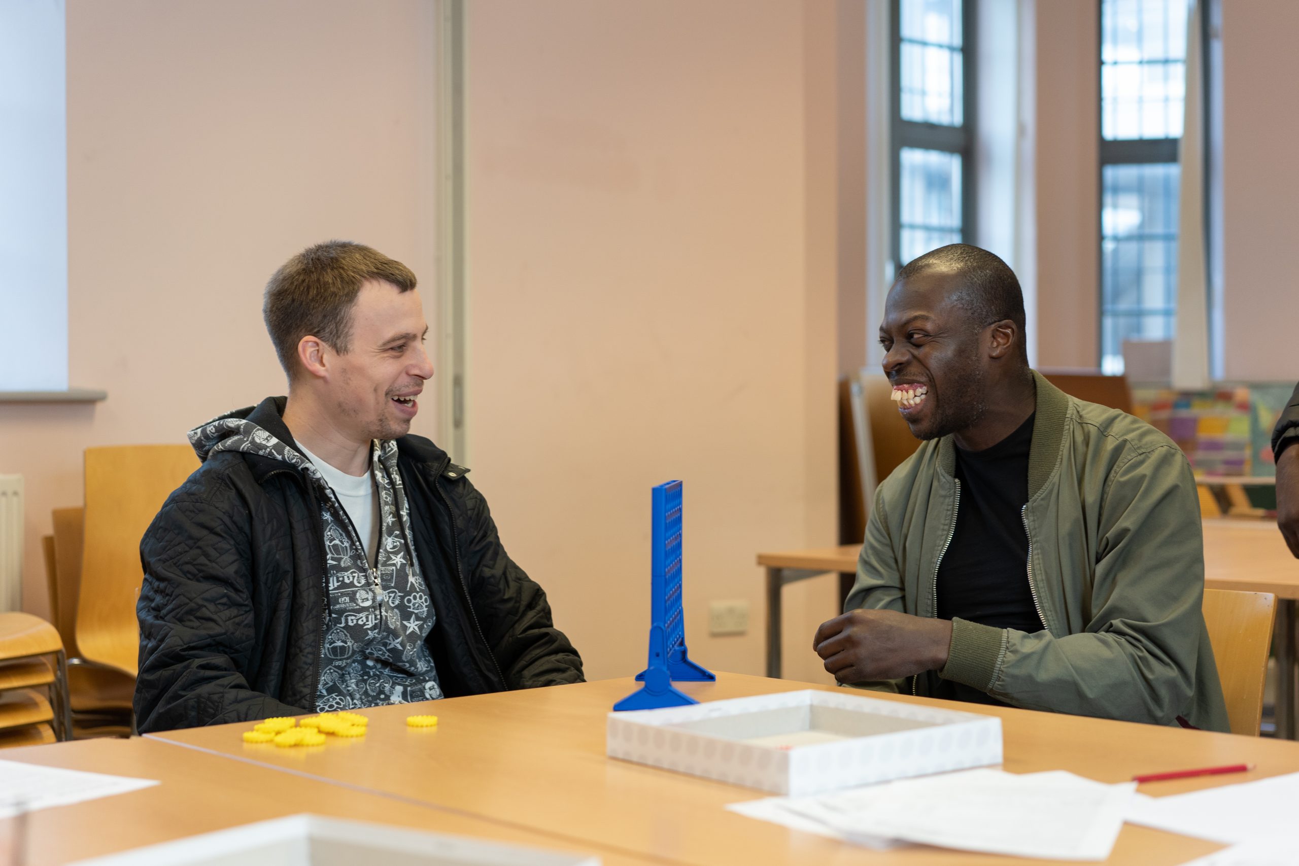 Two people sit in a room and play a game together at a table